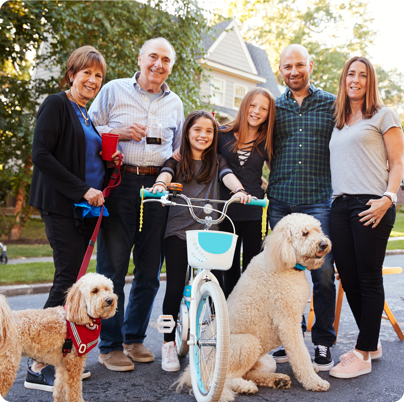 Family standing outside with their two goldendoodles at a neighborhood gathering